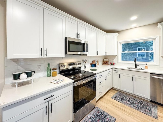 kitchen featuring white cabinetry, sink, stainless steel appliances, and light hardwood / wood-style floors