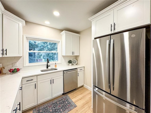 kitchen featuring tasteful backsplash, sink, white cabinets, light hardwood / wood-style floors, and stainless steel appliances