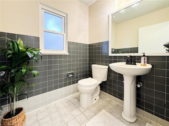 bathroom featuring toilet, tile patterned flooring, and tile walls