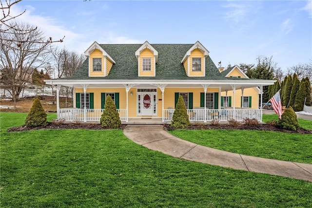 country-style home featuring covered porch, a shingled roof, and a front yard