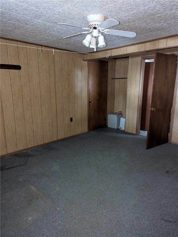 interior space with carpet, ceiling fan, and wood walls