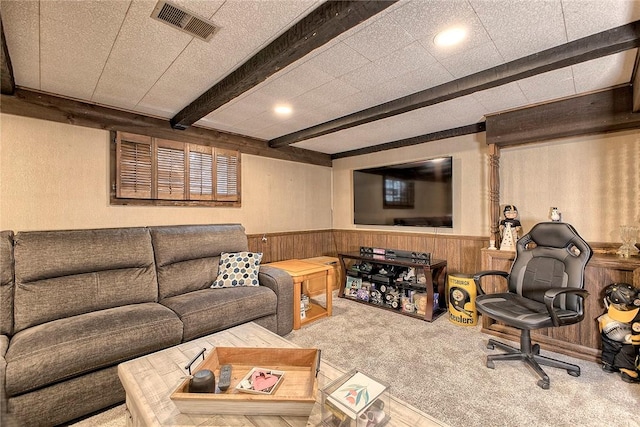 living room featuring beamed ceiling, carpet, and wood walls