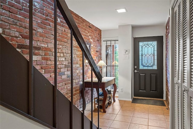 tiled foyer entrance featuring brick wall