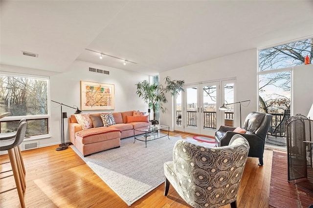 living room featuring french doors, wood-type flooring, and rail lighting