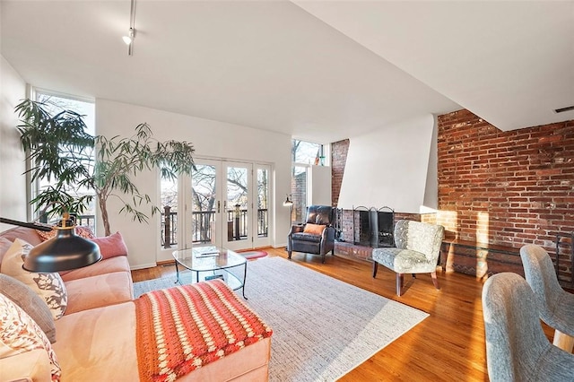 living room featuring french doors, brick wall, and wood-type flooring