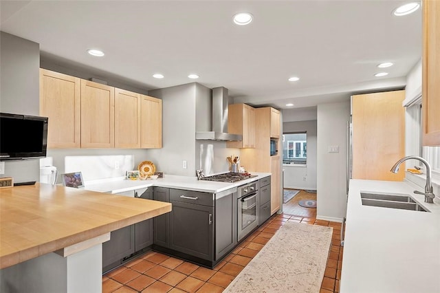 kitchen featuring wall chimney range hood, light tile patterned floors, gray cabinets, sink, and stainless steel appliances