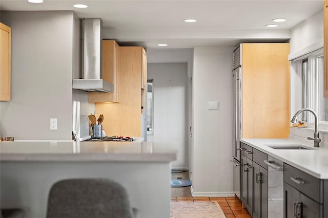 kitchen with wall chimney range hood, sink, gray cabinetry, light tile patterned flooring, and kitchen peninsula