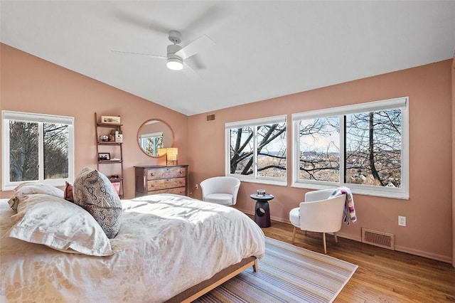 bedroom featuring multiple windows, hardwood / wood-style floors, vaulted ceiling, and ceiling fan