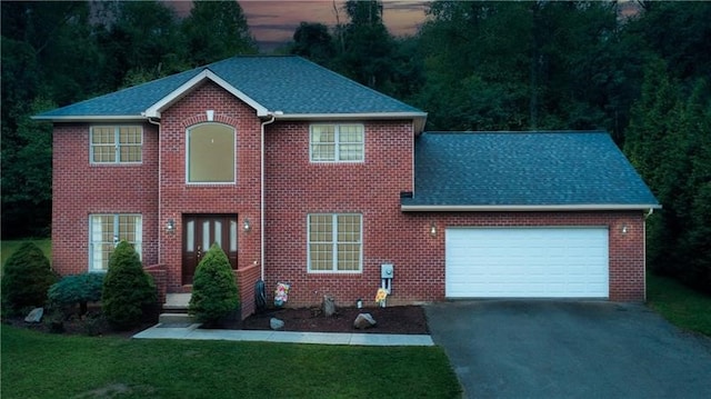 colonial inspired home featuring a garage and a lawn