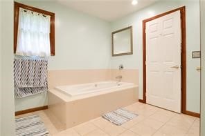 bathroom with tile patterned floors and a tub to relax in