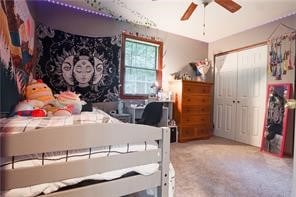 carpeted bedroom with ceiling fan and a closet