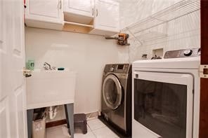 laundry area with cabinets, light tile patterned flooring, and washer and dryer