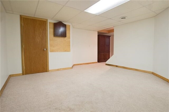 basement with a paneled ceiling and carpet flooring