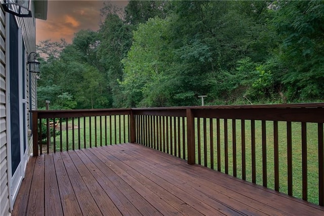 deck at dusk featuring a yard