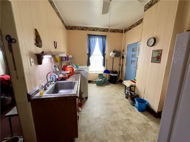 kitchen with ceiling fan, sink, and wood walls