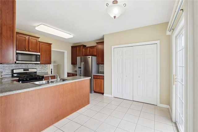 kitchen with sink, appliances with stainless steel finishes, light tile patterned flooring, decorative backsplash, and kitchen peninsula