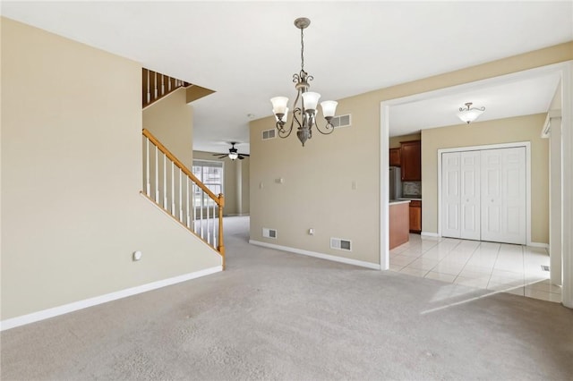 carpeted spare room with ceiling fan with notable chandelier