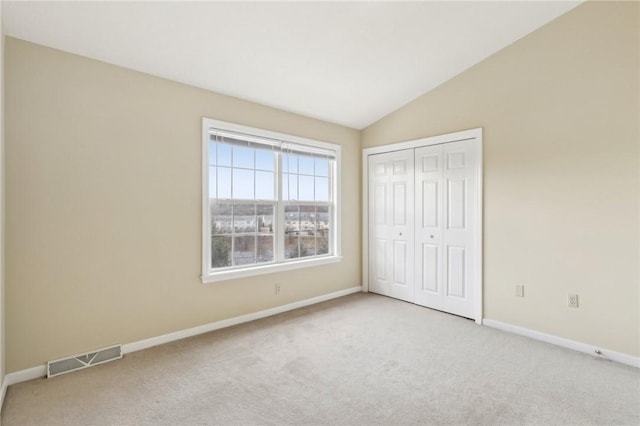 unfurnished bedroom with vaulted ceiling, light colored carpet, and a closet