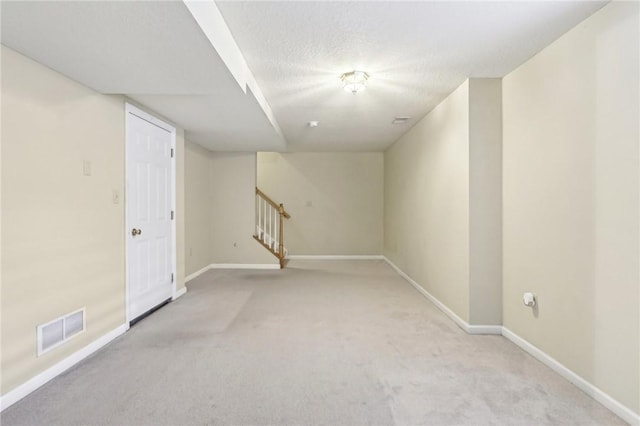 basement featuring light colored carpet and a textured ceiling