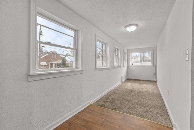 hallway featuring wood-type flooring and a textured ceiling