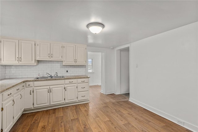 kitchen with sink, backsplash, light hardwood / wood-style flooring, and white cabinets