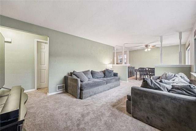 living room featuring a ceiling fan, visible vents, light carpet, and baseboards