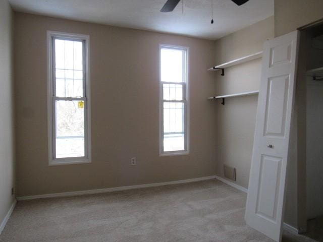 carpeted spare room featuring ceiling fan and plenty of natural light