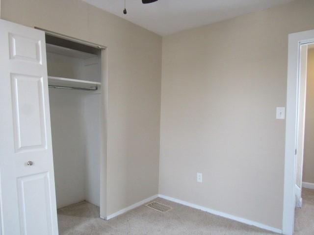 unfurnished bedroom with light carpet and a closet