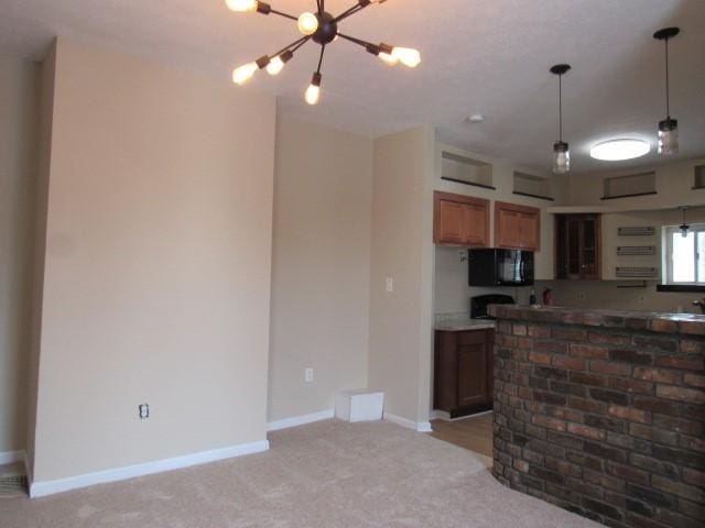 kitchen featuring light carpet, a chandelier, and decorative light fixtures