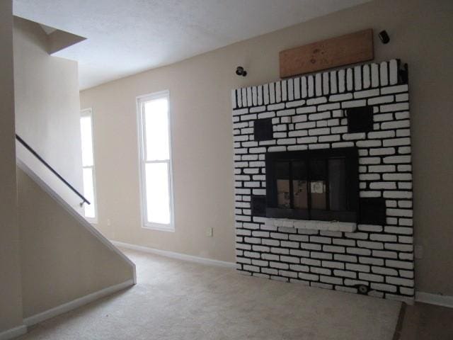 unfurnished living room featuring a brick fireplace and carpet