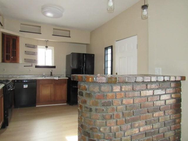 kitchen featuring decorative light fixtures, sink, light hardwood / wood-style flooring, and black appliances