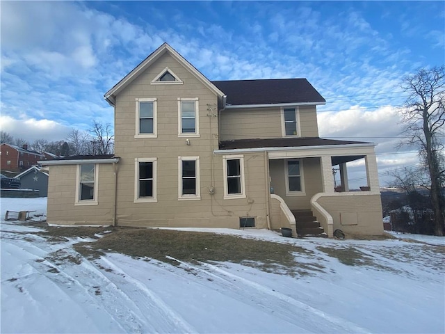 snow covered back of property with covered porch