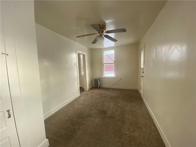 empty room featuring radiator, ceiling fan, and dark colored carpet