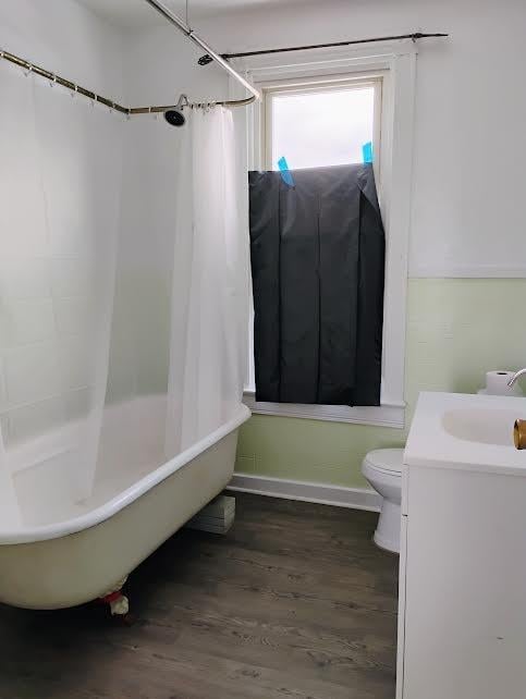 full bathroom featuring wood-type flooring, toilet, shower / tub combo, and vanity