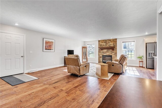 living room featuring a brick fireplace and light wood-type flooring