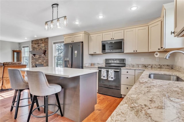 kitchen with sink, hanging light fixtures, stainless steel appliances, and cream cabinetry