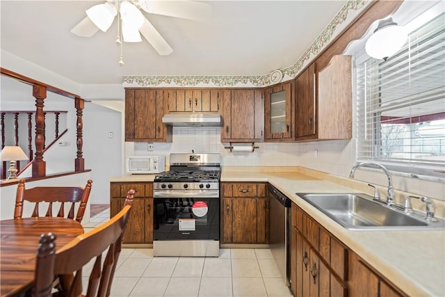 kitchen with appliances with stainless steel finishes, sink, backsplash, light tile patterned floors, and ceiling fan