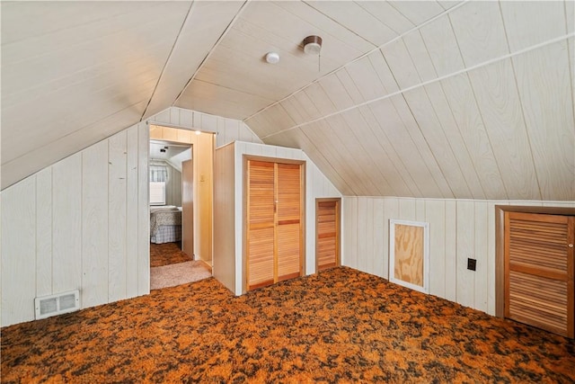 additional living space with lofted ceiling, wooden walls, and carpet