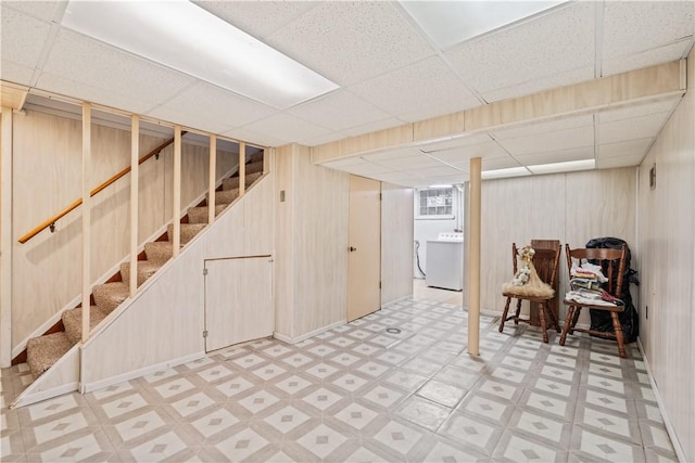 basement featuring washer / dryer, a paneled ceiling, and wooden walls