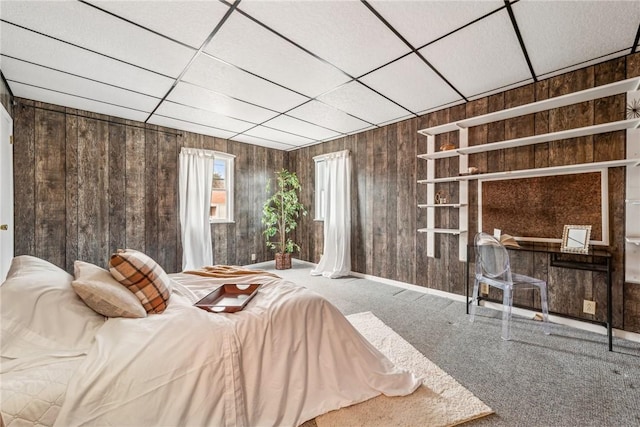 bedroom with carpet flooring, wooden walls, and a paneled ceiling