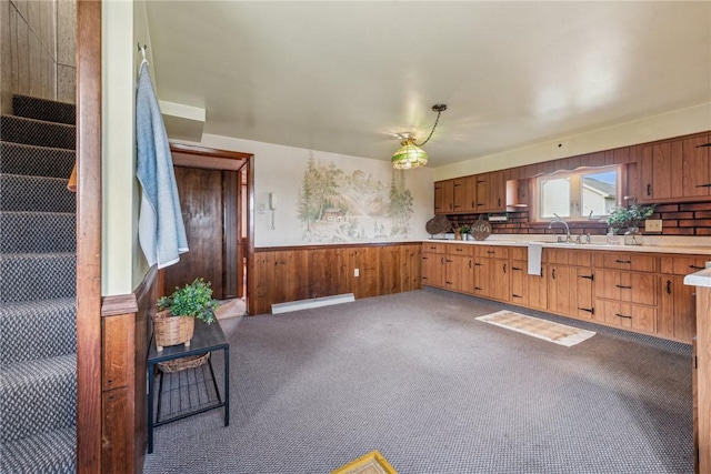 kitchen with hanging light fixtures, wooden walls, light colored carpet, and baseboard heating