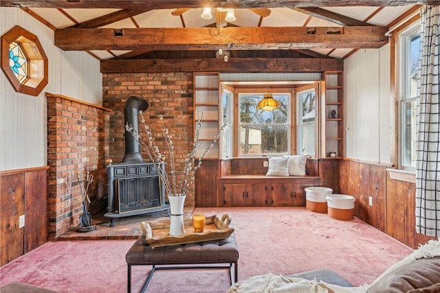 living room featuring wood walls, carpet floors, lofted ceiling with beams, and a wood stove