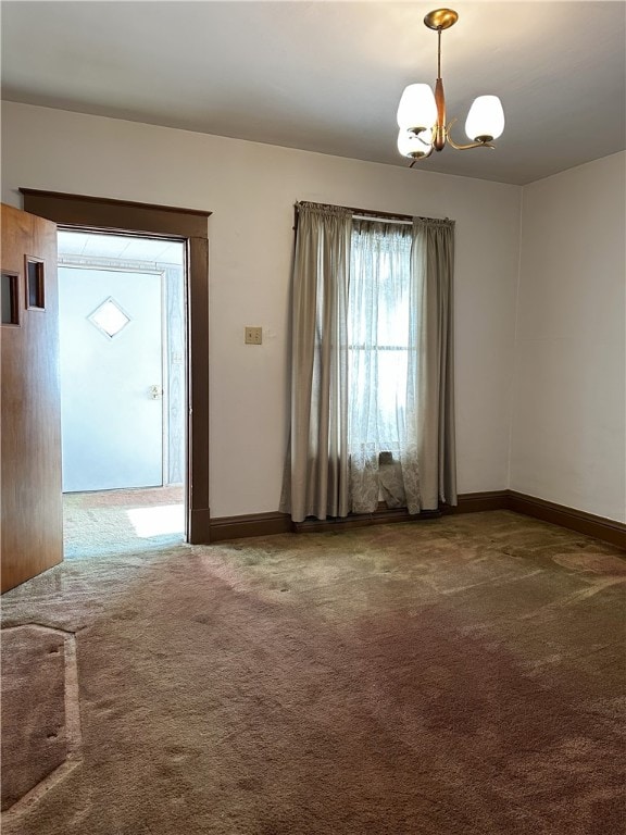 carpeted spare room with a chandelier