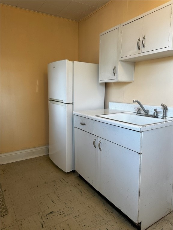 kitchen featuring white cabinetry, white fridge, and sink