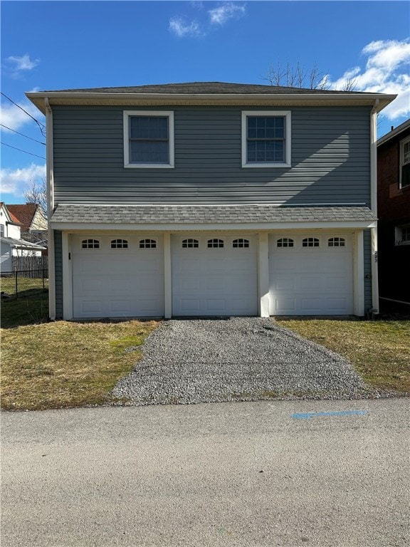 front facade featuring a garage and an outbuilding