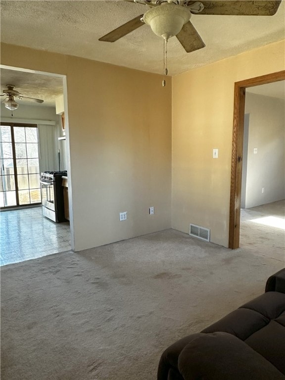 living room featuring a textured ceiling, carpet floors, and ceiling fan