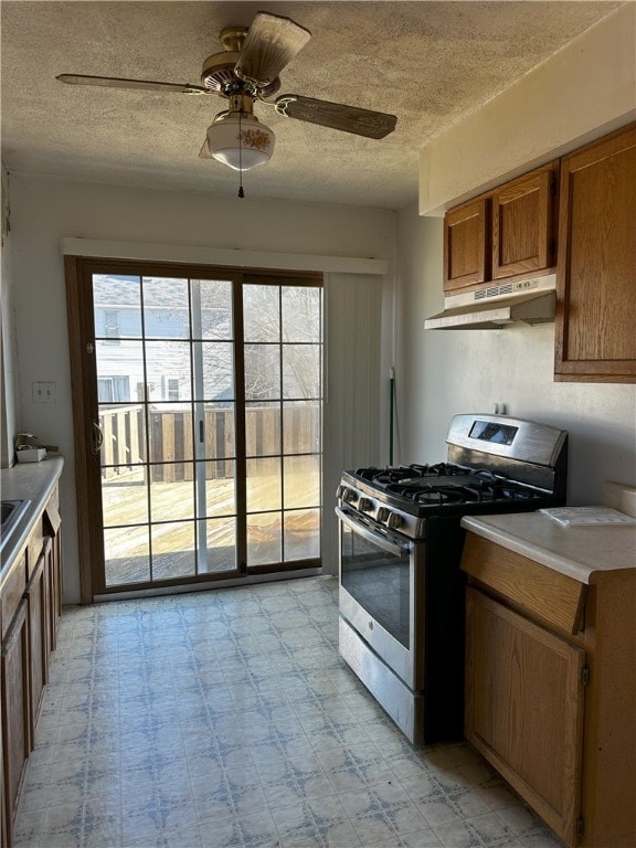 kitchen featuring ceiling fan, a textured ceiling, and stainless steel gas range oven