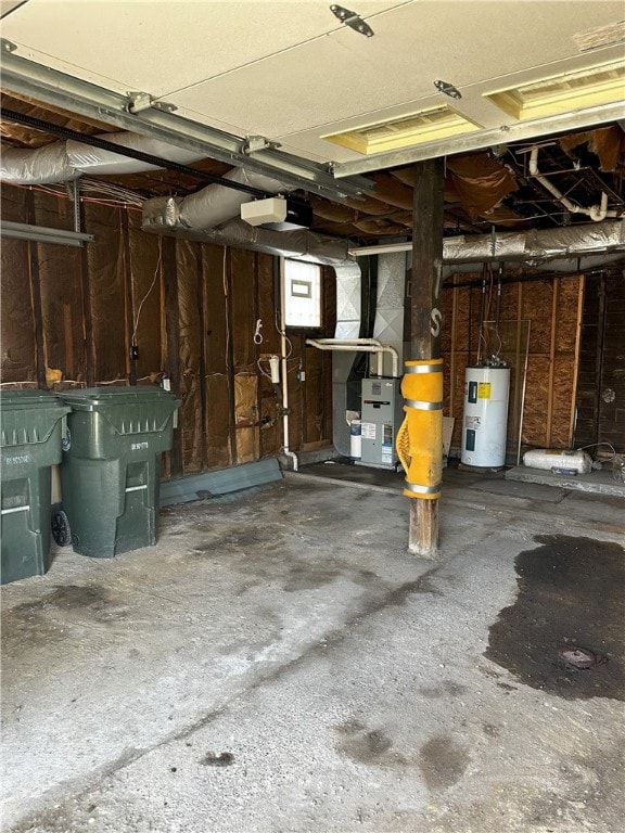 garage with a garage door opener, electric water heater, and heating unit