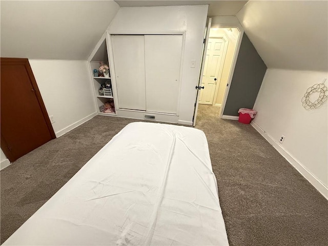 bedroom with lofted ceiling, dark carpet, and a closet