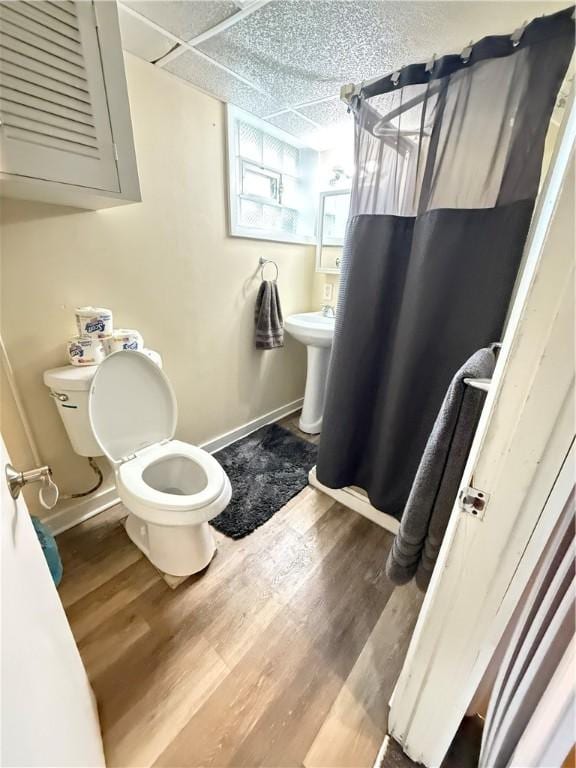 bathroom with a shower with curtain, wood-type flooring, a paneled ceiling, and toilet